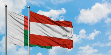 Madagaskar ve Avusturya bayrağı birlikte beyaz bulutlu mavi gökyüzüne karşı rüzgarda sallayarak. Diplomasi kavramı, uluslararası ilişkiler.