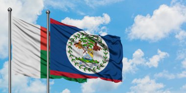 Madagaskar ve Belize bayrağı birlikte beyaz bulutlu mavi gökyüzüne karşı rüzgarda sallayarak. Diplomasi kavramı, uluslararası ilişkiler.