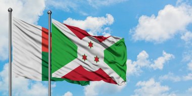 Madagaskar ve Burundi bayrağı birlikte beyaz bulutlu mavi gökyüzüne karşı rüzgarda sallayarak. Diplomasi kavramı, uluslararası ilişkiler.