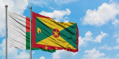 Madagaskar ve Grenada bayrağı birlikte beyaz bulutlu mavi gökyüzüne karşı rüzgarda sallayarak. Diplomasi kavramı, uluslararası ilişkiler.