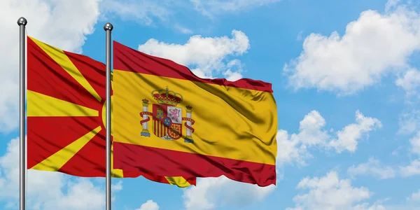 马其顿和西班牙国旗在风中飘扬，白云蓝天相聚。外交概念、国际关系. — 图库照片