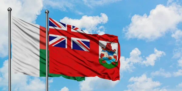 Bandera de Madagascar y Bermudas ondeando en el viento contra el cielo azul nublado blanco juntos. Concepto diplomático, relaciones internacionales . — Foto de Stock