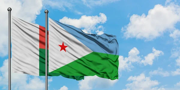 Madagascar y la bandera de Djibouti ondeando en el viento contra el cielo azul nublado blanco juntos. Concepto diplomático, relaciones internacionales . — Foto de Stock