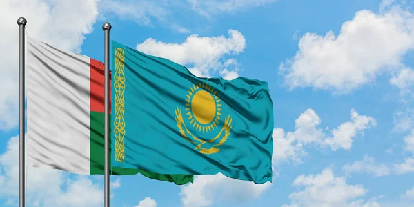 Bandera de Madagascar y Kazajstán ondeando en el viento contra el cielo azul nublado blanco juntos. Concepto diplomático, relaciones internacionales . — Foto de Stock