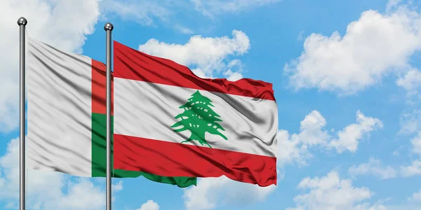 Bandera de Madagascar y Líbano ondeando en el viento contra el cielo azul nublado blanco juntos. Concepto diplomático, relaciones internacionales . — Foto de Stock