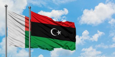 Madagaskar ve Libya bayrağı birlikte beyaz bulutlu mavi gökyüzüne karşı rüzgarda sallayarak. Diplomasi kavramı, uluslararası ilişkiler.