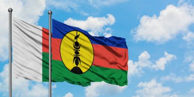 Madagaskar ve Yeni Kaledonya bayrağı birlikte beyaz bulutlu mavi gökyüzüne karşı rüzgarda sallayarak. Diplomasi kavramı, uluslararası ilişkiler.