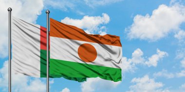 Madagaskar ve Nijer bayrağı birlikte beyaz bulutlu mavi gökyüzüne karşı rüzgarda sallayarak. Diplomasi kavramı, uluslararası ilişkiler.