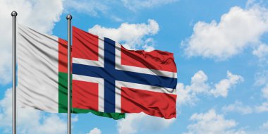 Madagaskar ve Norveç bayrağı birlikte beyaz bulutlu mavi gökyüzüne karşı rüzgarda sallayarak. Diplomasi kavramı, uluslararası ilişkiler.