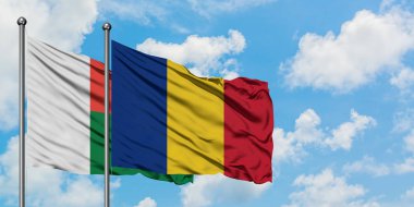 Madagaskar ve Romanya bayrağı birlikte beyaz bulutlu mavi gökyüzüne karşı rüzgarda sallayarak. Diplomasi kavramı, uluslararası ilişkiler.