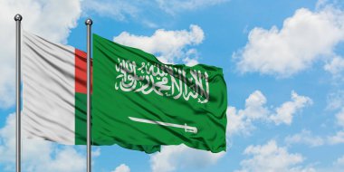 Madagaskar ve Suudi Arabistan bayrağı birlikte beyaz bulutlu mavi gökyüzüne karşı rüzgarda sallayarak. Diplomasi kavramı, uluslararası ilişkiler.