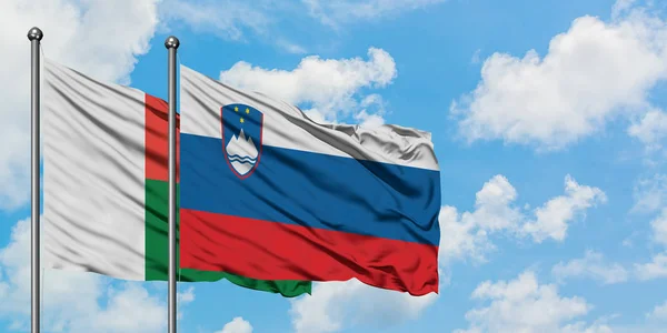 Madagascar and Slovenia flag waving in the wind against white cloudy blue sky together. Diplomacy concept, international relations. — Stock Photo, Image