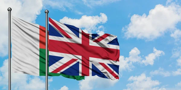 马达加斯加和英国国旗在风中飘扬，白云蓝天相联。外交概念、国际关系. — 图库照片