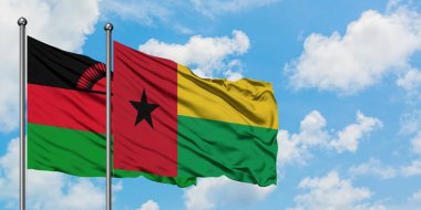 Malavi ve Gine Bissau bayrağı birlikte beyaz bulutlu mavi gökyüzüne karşı rüzgarda sallayarak. Diplomasi kavramı, uluslararası ilişkiler.