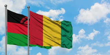 Malavi ve Gine bayrağı birlikte beyaz bulutlu mavi gökyüzüne karşı rüzgarda sallayarak. Diplomasi kavramı, uluslararası ilişkiler.