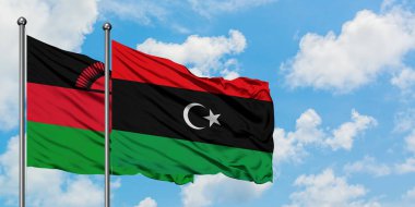 Malavi ve Libya bayrağı birlikte beyaz bulutlu mavi gökyüzüne karşı rüzgarda sallayarak. Diplomasi kavramı, uluslararası ilişkiler.