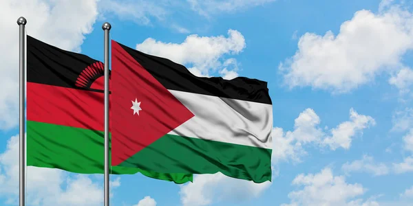 Bandera de Malawi y Jordania ondeando en el viento contra el cielo azul nublado blanco juntos. Concepto diplomático, relaciones internacionales . — Foto de Stock
