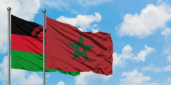 Bandera de Malawi y Marruecos ondeando en el viento contra el cielo azul nublado blanco juntos. Concepto diplomático, relaciones internacionales . — Foto de Stock