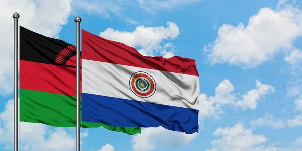 Bandera de Malawi y Paraguay ondeando en el viento contra el cielo azul nublado blanco juntos. Concepto diplomático, relaciones internacionales . — Foto de Stock