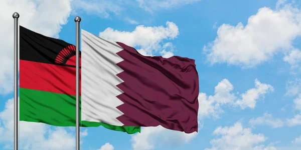 Bandera de Malawi y Qatar ondeando en el viento contra el cielo azul nublado blanco juntos. Concepto diplomático, relaciones internacionales . — Foto de Stock