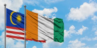 Malezya ve Fildişi Sahili bayrağı birlikte beyaz bulutlu mavi gökyüzüne karşı rüzgarda sallayarak. Diplomasi kavramı, uluslararası ilişkiler.