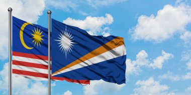 Malezya ve Marshall Adaları bayrağı birlikte beyaz bulutlu mavi gökyüzüne karşı rüzgarda sallayarak. Diplomasi kavramı, uluslararası ilişkiler.