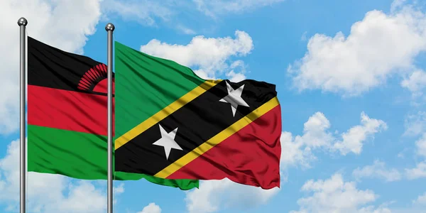 Malawi e Saint Kitts E Nevis sventolano la bandiera contro il bianco cielo azzurro nuvoloso insieme. Concetto di diplomazia, relazioni internazionali . — Foto Stock