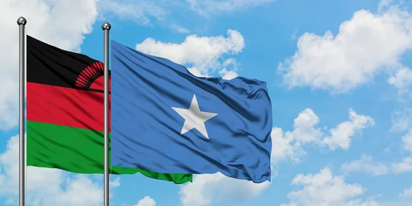 Bandera de Malawi y Somalia ondeando en el viento contra el cielo azul nublado blanco juntos. Concepto diplomático, relaciones internacionales . — Foto de Stock
