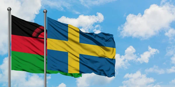 马拉维和瑞典国旗在风中飘扬，与白云蓝天相一起。外交概念、国际关系. — 图库照片