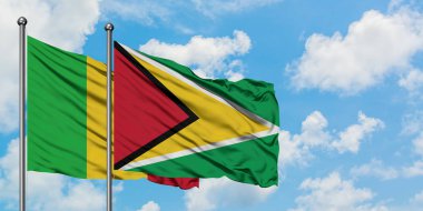 Mali ve Guyana bayrağı birlikte beyaz bulutlu mavi gökyüzüne karşı rüzgarda sallayarak. Diplomasi kavramı, uluslararası ilişkiler.