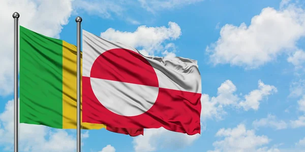 Bandera de Malí y Groenlandia ondeando en el viento contra el cielo azul nublado blanco juntos. Concepto diplomático, relaciones internacionales . — Foto de Stock