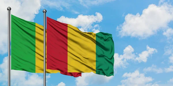Bandera de Malí y Guinea ondeando en el viento contra el cielo azul nublado blanco juntos. Concepto diplomático, relaciones internacionales . — Foto de Stock