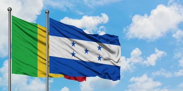 Bandera de Malí y Honduras ondeando en el viento contra el cielo azul nublado blanco juntos. Concepto diplomático, relaciones internacionales . — Foto de Stock