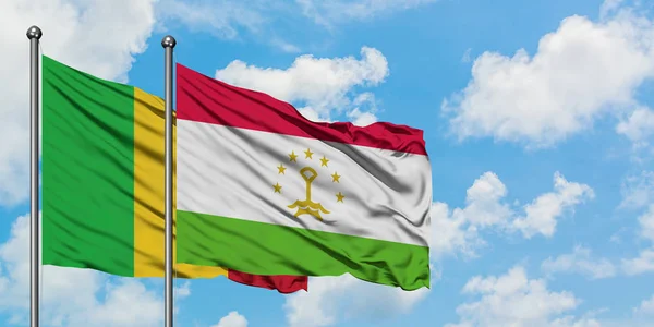 Bandera de Malí y Tayikistán ondeando en el viento contra el cielo azul nublado blanco juntos. Concepto diplomático, relaciones internacionales . — Foto de Stock