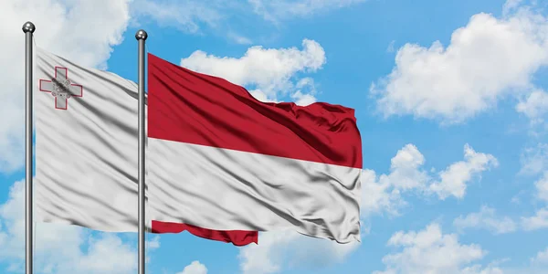 Malta e a Indonésia acenando com o vento contra o céu azul nublado branco juntos. Conceito de diplomacia, relações internacionais . — Fotografia de Stock