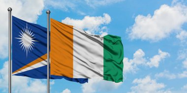 Marshall Adaları ve Fildişi Sahili bayrağı birlikte beyaz bulutlu mavi gökyüzüne karşı rüzgarda sallayarak. Diplomasi kavramı, uluslararası ilişkiler.