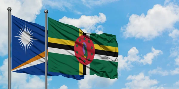 Marshallinseln und Dominica-Flagge wehen gemeinsam im Wind gegen den wolkenverhangenen blauen Himmel. Diplomatie-Konzept, internationale Beziehungen. — Stockfoto