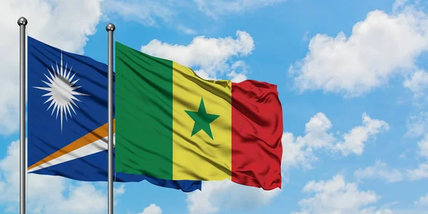 Bandera de las Islas Marshall y Senegal ondeando en el viento contra el cielo azul nublado blanco juntos. Concepto diplomático, relaciones internacionales . — Foto de Stock
