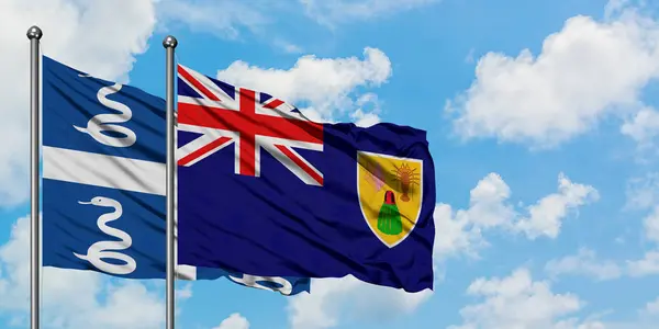 Martinica y las Islas Turcas y Caicos ondean en el viento contra el cielo azul nublado blanco juntos. Concepto diplomático, relaciones internacionales . — Foto de Stock