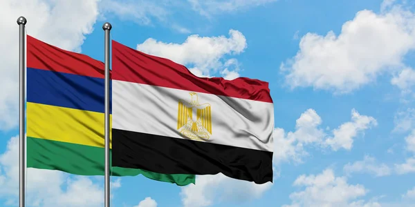 Mauricio y Egipto bandera ondeando en el viento contra blanco cielo azul nublado juntos. Concepto diplomático, relaciones internacionales . — Foto de Stock