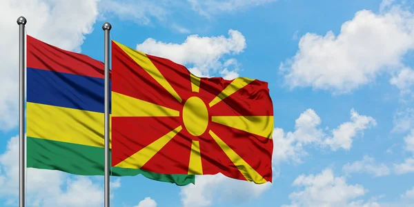 Bandera de Mauricio y Macedonia ondeando en el viento contra el cielo azul nublado blanco juntos. Concepto diplomático, relaciones internacionales . — Foto de Stock