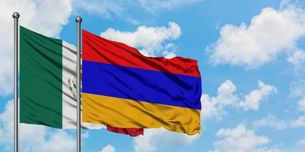 Bandera de México y Armenia ondeando en el viento contra el cielo azul nublado blanco juntos. Concepto diplomático, relaciones internacionales . — Foto de Stock