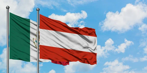 Bandera de México y Austria ondeando en el viento contra el cielo azul nublado blanco juntos. Concepto diplomático, relaciones internacionales . — Foto de Stock