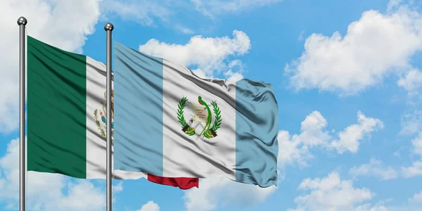 Bandera de México y Guatemala ondeando en el viento contra el cielo azul nublado blanco juntos. Concepto diplomático, relaciones internacionales . —  Fotos de Stock