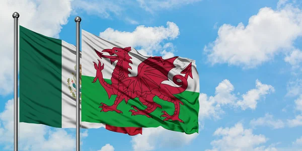 Bandeira do México e do País de Gales agitando no vento contra o céu azul nublado branco juntos. Conceito de diplomacia, relações internacionais . — Fotografia de Stock