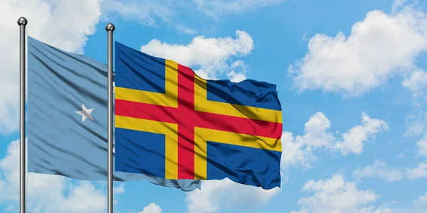 Micronesia and Aland Islands flag waving in the wind against white cloudy blue sky together. Diplomacy concept, international relations. — Stock Photo, Image