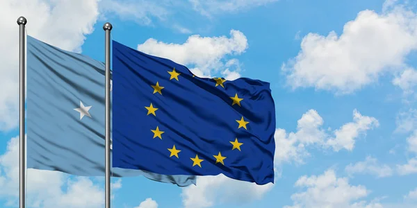 Micronésia e bandeira da União Europeia agitando no vento contra o céu azul nublado branco juntos. Conceito de diplomacia, relações internacionais . — Fotografia de Stock
