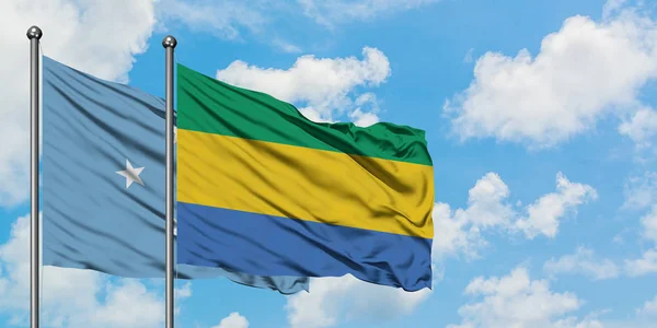密克罗尼西亚和加蓬国旗在风中飘扬，与白云相间的蓝天相联。外交概念、国际关系. — 图库照片