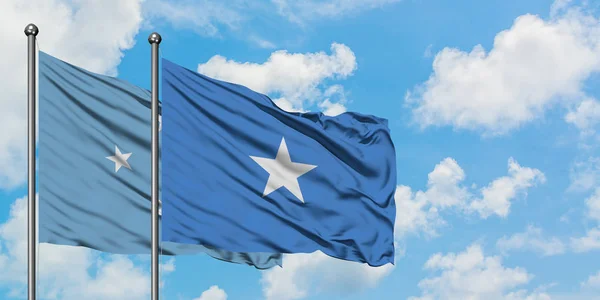 Bandera de Micronesia y Somalia ondeando en el viento contra el cielo azul nublado blanco juntos. Concepto diplomático, relaciones internacionales . — Foto de Stock