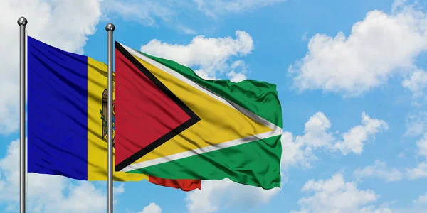 Bandera de Moldavia y Guyana ondeando en el viento contra el cielo azul nublado blanco juntos. Concepto diplomático, relaciones internacionales . — Foto de Stock